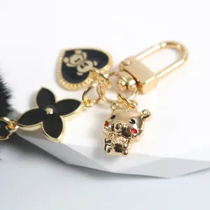 Cute golden metal keychain featuring bear heart tag, tiger charm and black fur pompom