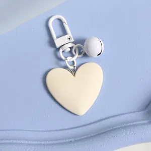 Detailed view of an ivory heart keychain with matching lobster clasp and bell accessory