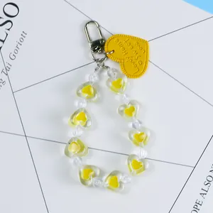Macro detail of yellow leather heart pendant with transparent acrylic bead chain accessory