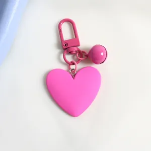 Detail of pink heart-shaped keychain with matte finish and matching bell ornament