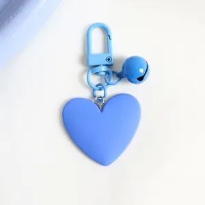 Detail of light blue heart-shaped keychain with matching bell and matte finish spring hook