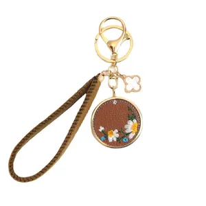 Brown leather daisy embroidery keychain with four-leaf clover charm and wrist strap