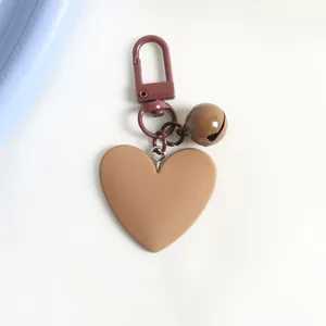 Macro detail of matte brown heart pendant keychain with matching bell and metal clasp