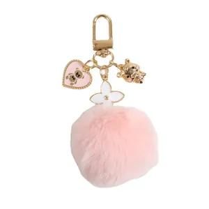 Pink fluffy faux fur pompom keychain with gold heart bear charms and white flower