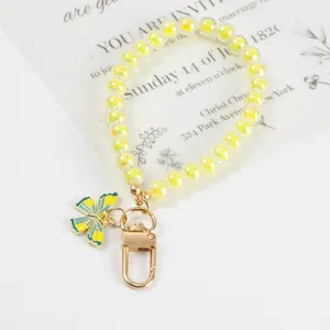 Macro view of a beaded keychain with yellow aurora beads and butterfly enamel pendant
