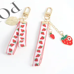 Detail of strawberry charm keychains with red fruit patterns on white ribbons