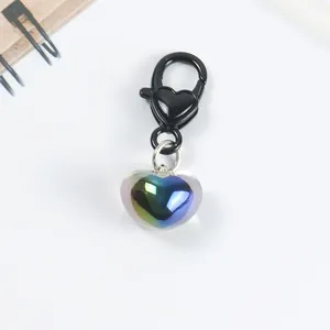 Macro detail of iridescent heart pendant with black spring clasp on white background