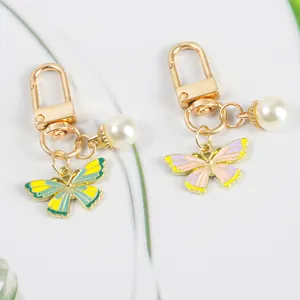 Detail of butterfly keychain with faux pearls and colorful enamel on a white background