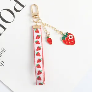 Detail of strawberry keychain with printed ribbon and crystal studded fruit charm