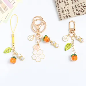Macro detail of persimmon and peanut charms on a gold keychain with white cherry blossom