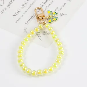 Macro view of light yellow beaded keychain featuring a golden clasp and butterfly charm