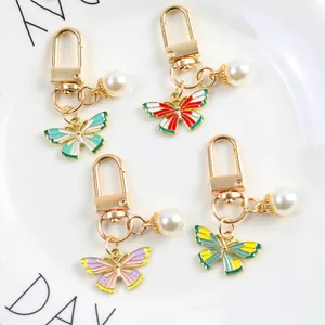 Set of four colorful butterfly pendants with pearls for bags and keychains in a white dish