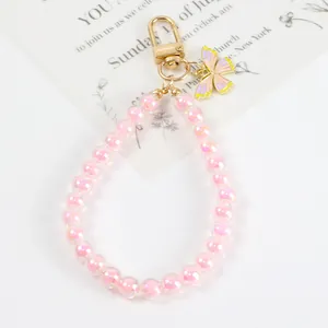 Close-up of pink iridescent beaded keychain with a golden butterfly charm and metal clasp