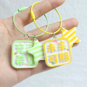 Detail of green and yellow square pendants with hopeful Chinese quotes on keychains