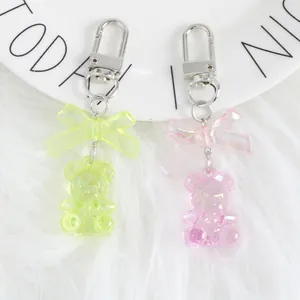 Close-up of pink and yellow crystal bear keychains with bows on a plush white background