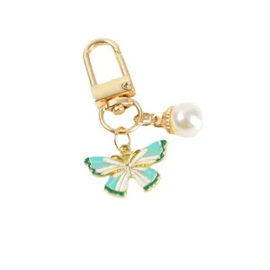 Golden keychain featuring mint green enamel butterfly pendant and white pearl charm