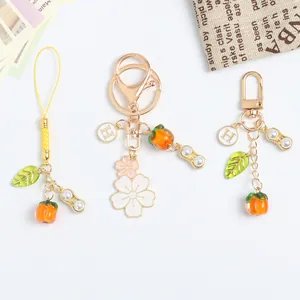 Persimmon and peanut keychain charms with golden leaf and 'H' pendant for bags
