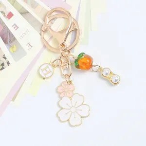 Detail of keychain featuring gold peanut charms, orange persimmon bead and sakura flowers