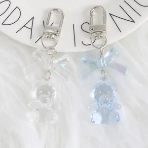 Cute colorful crystal bear keychain pendants with iridescent bows on white plush background