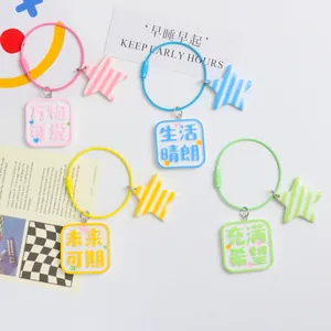 Colorful square keychains with star charms and positive quotes in four vibrant candy colors
