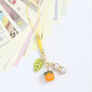 Detail of persimmon and peanut charms on yellow lanyard for bags or Airpods