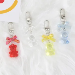 Close-up of four colorful translucent gummy bear pendants with bows on plush background
