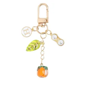 Golden persimmon and peanut keychain pendant with green leaf and H-initial charm