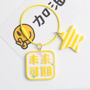 Macro detail of yellow square acrylic keychain with star charm and bead on steel ring