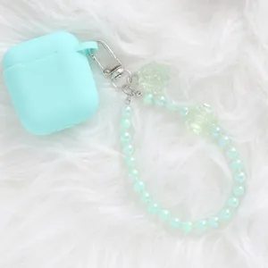 Close-up of mint green headphone case with translucent rose beads on white fur