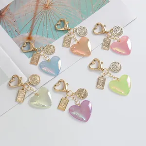 Detailed close-up of colorful iridescent heart keychains with golden coin charms