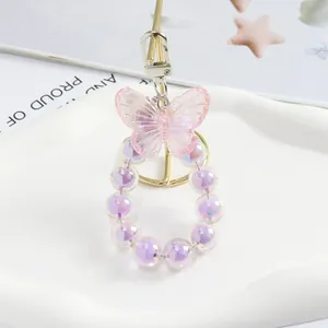 Dettaglio macro del ciondolo a farfalla rosa con perline viola su vassoio bianco