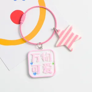 Close-up of pink star and square tag pendant on a steel wire keychain for bags