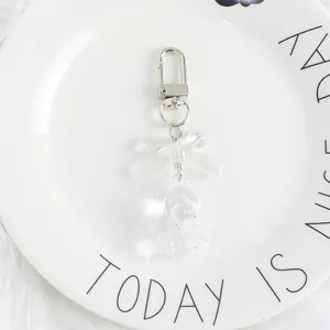 Close-up of a clear acrylic teddy bear keychain with a transparent bow and metal clasp