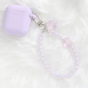 Detail of lavender silicone AirPods case with floral bead keychain on faux fur background