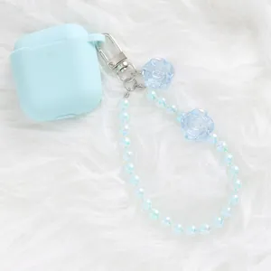Close-up of light blue AirPods case with iridescent crystal flower beaded lanyard charm