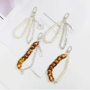 Détail de porte-clés à double chaîne avec perles, maillons ambre et pendentifs cœur