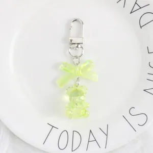 Close-up of a lime green crystal bear keychain with a translucent bow on a white plate