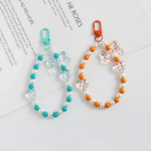 Dettaglio di ciondoli per telefono fatti a mano con perle, fiocchi e cuori in due colori