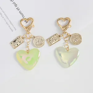 Macro detail of heart-shaped keychains featuring embossed metal coins and aurora acrylic charms