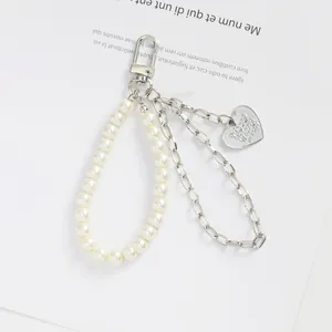 Détail du porte-clés à double chaîne en métal avec perles blanches et pendentif cœur