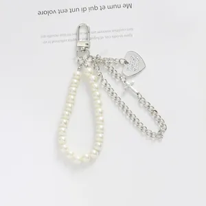 Détail d'un porte-clés à chaîne argentée avec perles et un pendentif métallique en cœur