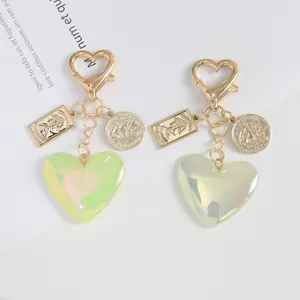 Macro view of iridescent resin heart pendant and golden alloy sailboat coin on keychain