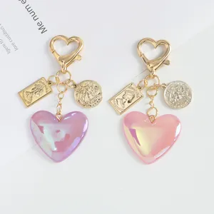 Macro shot of iridescent resin heart keychains with vintage coin charms and gold hooks