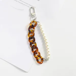 Détail du porte-clés à double chaîne avec maillons acrylique ambrés et perles blanches