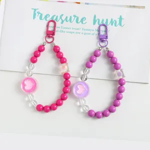 Close-up of pink and purple beaded heart charms with lobster clasp on a magazine