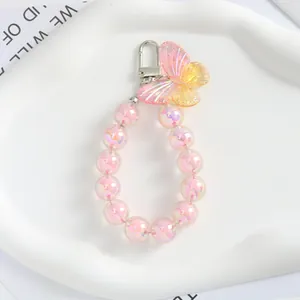 Dettaglio del ciondolo a farfalla rosa sfumato con perline dai riflessi iridescenti