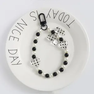 Dettaglio catena di perle bianche e nere con ciondoli a cuore e fiocco a pois