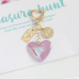 Detailed close-up of pink iridescent heart pendant with vintage golden coin charms