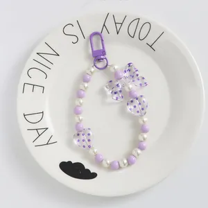 Dettaglio del portachiavi con perline viola a cuore e fiocco su un vassoio di ceramica