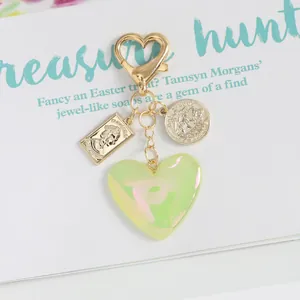 Macro detail of heart-shaped iridescent pendant with Elizabeth II coin and sailboat charm